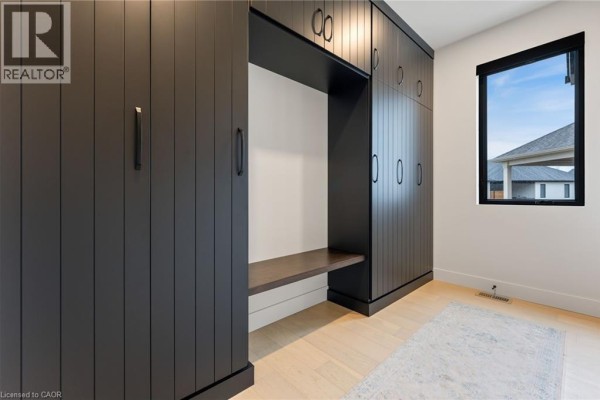 Spacious hallway with light wood flooring, decorative plant, and view into living area - 12 Macneil Court, Port Burwell