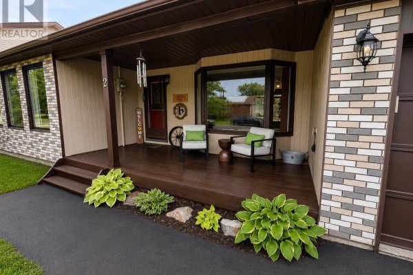 Close-up of the covered porch with seating, plants, and a garage door. - 12 Maple St, Wawa