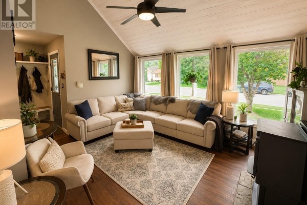 Living room with a large sectional sofa, armchair, ottoman, and large windows. - 12 Maple St, Wawa