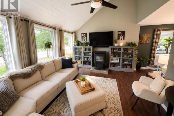 Living room with a fireplace, television, display cabinets, sofa, and armchair. - 12 Maple St, Wawa