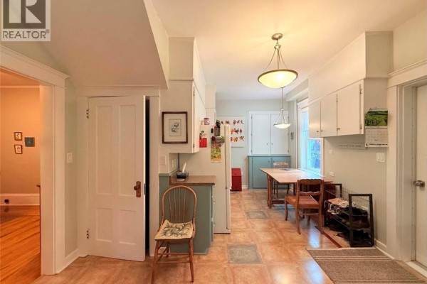 Kitchen with a breakfast nook, white cabinets, teal lower cabinets, and a doorway to another room. - 12 Matheson Avenue, Edmundston