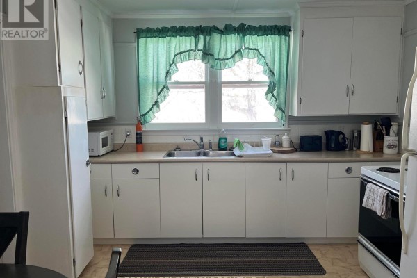 Kitchen with white cabinets, a sink, appliances, and green ruffled curtains. - 12 Mccullough Street, Marathon