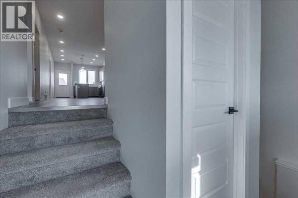 Empty bedroom with grey carpet, white trim, and a large window. - 12 Memorial Parkway, Rural Red Deer County