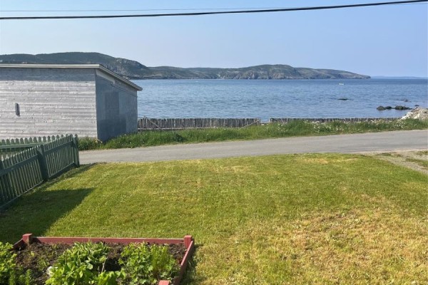 View of Bonavista Bay with a shed, grassy lawn, and wooden fence in the foreground. - 12 Mockbeggar Road, Bonavista