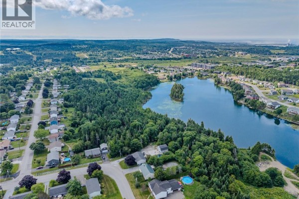 Aerial view of residential homes bordering a large lake and wooded area in Saint John. - 12 Mosaic Drive, Saint John