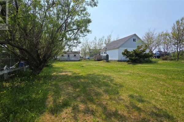 Rear view of the house and a small outbuilding in a grassy yard. - 12 Parsons Lane, Twillingate