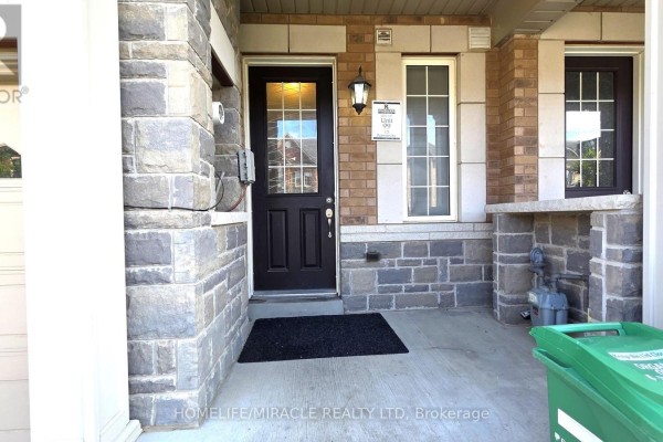 Kitchen with dark brown cabinets, granite island, and white appliances. - 12 Pearman Crescent, Brampton