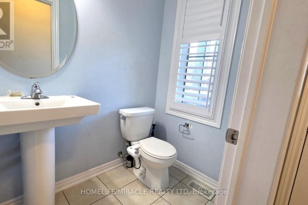 Kitchen with island, dark cabinets, white refrigerator, and doorway to hallway. - 12 Pearman Crescent, Brampton