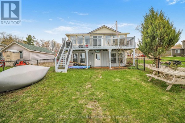 Rear exterior of the house with a deck, stairs, a small dock, a canoe, and a picnic table on the lawn. - 12 Robins Point Road, Tay