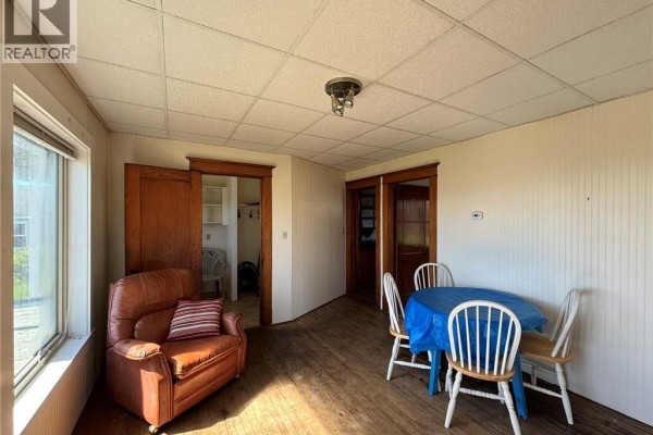 Sunroom with a leather armchair, dining table set with chairs, and a view through the window. - 12 Sc Breakwater, Grand Manan