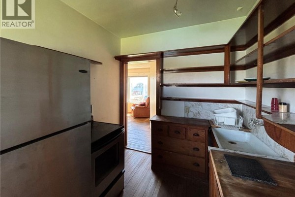 Kitchen with stainless steel refrigerator, wooden cabinets, sink, and doorway to another room. - 12 Sc Breakwater, Grand Manan