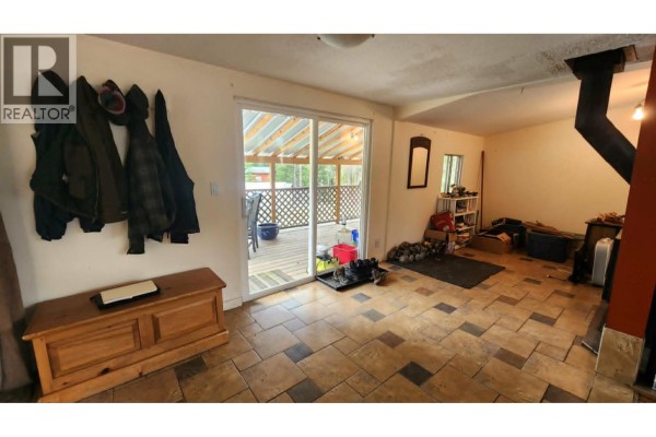 Interior room with a wooden chest, coats hanging, a sliding glass door, and a wood stove. - 12 Specht Road, Cherryville