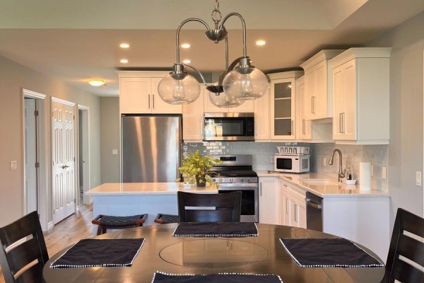 View of kitchen and dining area with dark wood table and white cabinets. - 12 Sweetwater Drive S, Goderich)