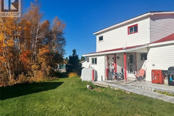 Side view of the white house and an old wooden garage structure surrounded by greenery. - 12 Thibodeau Lane, Baie Sainte Anne
