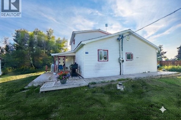 Side view of the house showing a wooden deck with a BBQ and potted plants. - 12 Thibodeau Lane, Baie Sainte Anne