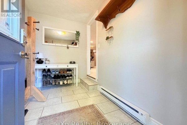 Foyer with light grey walls, tiled floor, a shoe rack, and a large mirror above a console table. - 12 Union Street N, Brockton