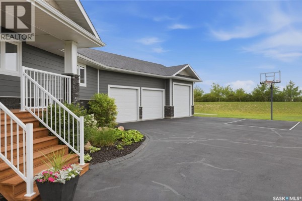 Close-up of the wooden front steps with white railings and a planter box leading to a dark grey house. - 12 Valley Ridge Road, Last Mountain Lake