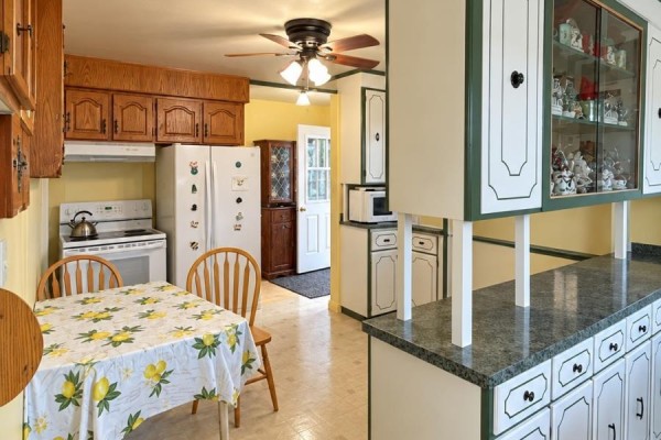 Kitchen with white appliances, wooden cabinets, and a dining table. - 12 Welsh's Lane, Pouch Cove
