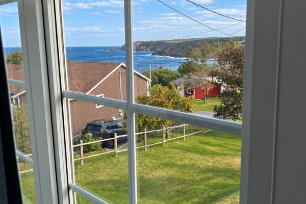 Ocean view from a window overlooking houses and a fence. - 12 Welsh's Lane, Pouch Cove