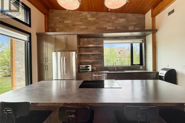 Outdoor patio area with Adirondack chairs, fire pit, and wooden decking. - 12/14 Bruin Boulevard, Candle Lake