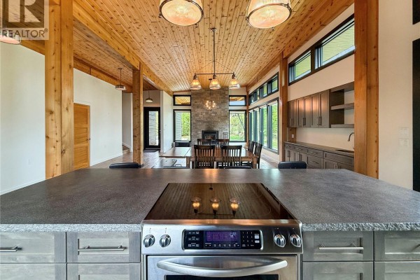 Kitchen island with stovetop, and dining area with fireplace visible beyond. - 12/14 Bruin Boulevard, Candle Lake
