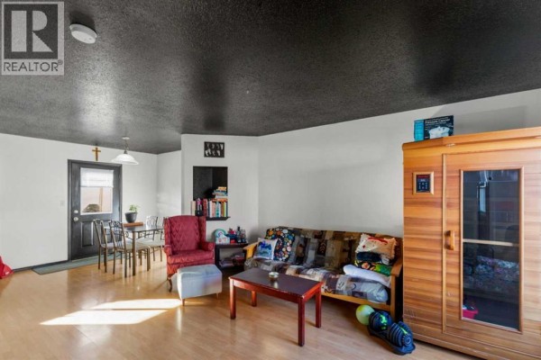 Living and dining area with a sofa, armchair, and dining table, and a wooden sauna. - 120, 10150 121 Avenue, Grande Prairie