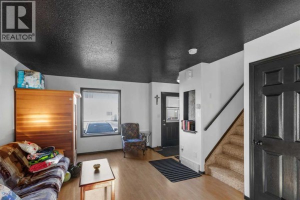 Living room with a sofa, armchair, and a view of the street through the window. - 120, 10150 121 Avenue, Grande Prairie