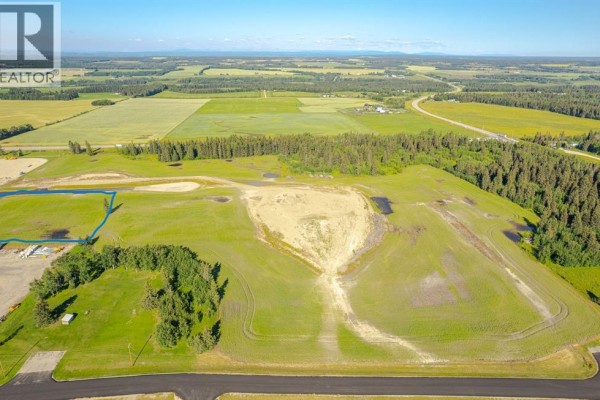 Wide aerial shot of rural land with cleared areas, trees, and distant agricultural fields. - 120, 32532 Range Road 42, Rural Mountain View County