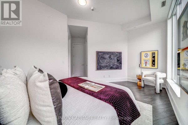 Bedroom with a bed, dark wood floors, and art on the walls. - 120 - 25 Adra Grado Way, Toronto