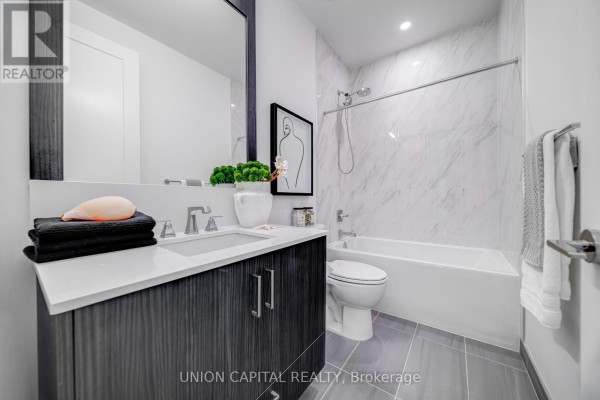 Bathroom with a vanity, toilet, bathtub, and marble tile walls. - 120 - 25 Adra Grado Way, Toronto