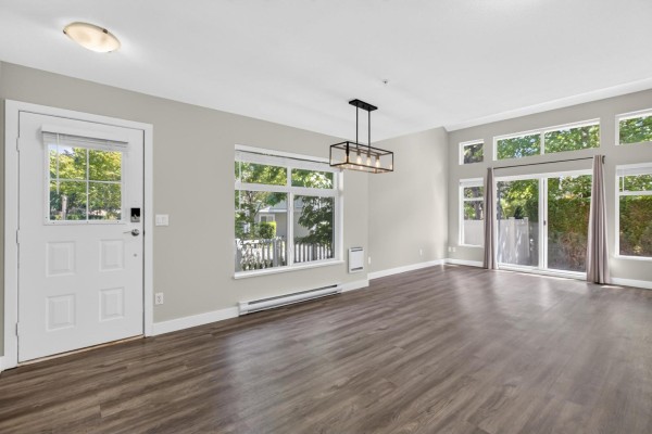 Spacious open concept living and dining area with white door and multiple windows. - 120 20033 70 Avenue, Langley
