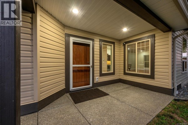 Spacious living area featuring a kitchen island, bar seating, and natural light. - 120 2205 Robert Lang Dr, Courtenay