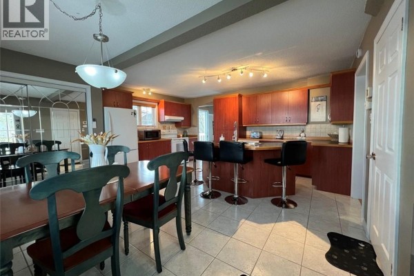 View of the kitchen and dining area, featuring wooden cabinetry and bar seating. - 120 34th Avenue, Edmundston