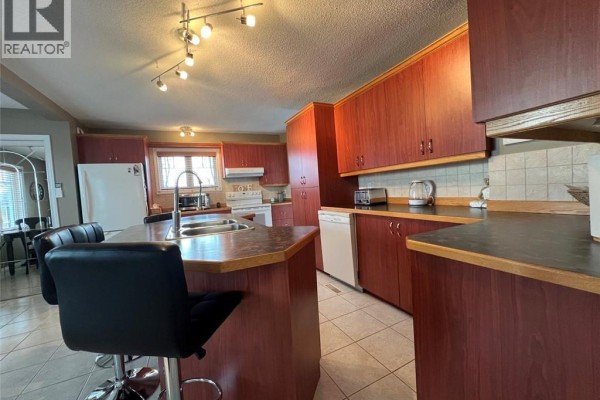 Close-up of the kitchen with wooden cabinets, stainless steel appliances, and a center island. - 120 34th Avenue, Edmundston