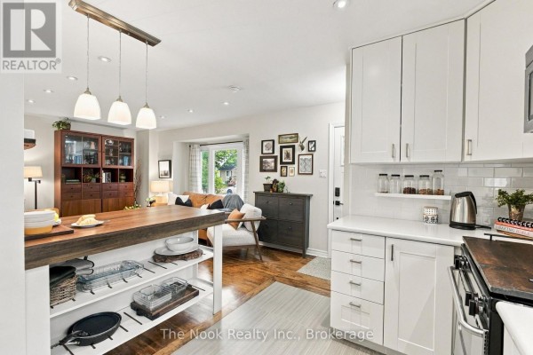 Open-concept kitchen and living room with white cabinets, hardwood floors, and a bay window. - 120 Admiral Road, Ajax