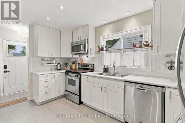 White kitchen with stainless steel appliances, a double sink, and a window above the counter. - 120 Admiral Road, Ajax