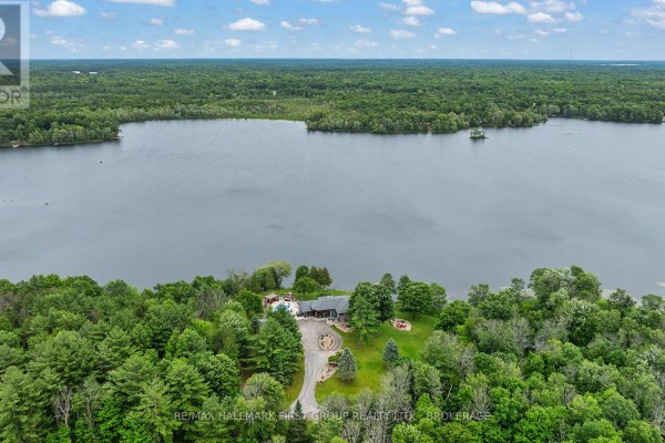 Aerial view of a large lakefront property with a house and surrounding forest. - 120 Black Lake Route 1, Tay Valley