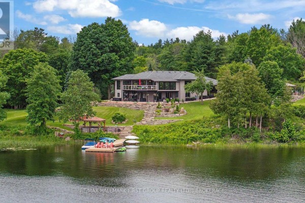 View of the lake from the backyard with a stone patio and seating area. - 120 Black Lake Route 1, Tay Valley