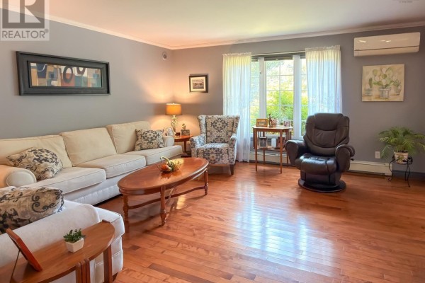 Living room with beige sofa, patterned armchair, recliner, and hardwood floors. - 120 Dawson Heights, Pine Grove