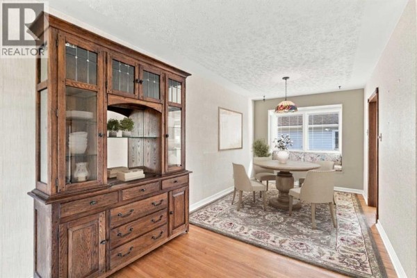 Dining area with a round table, chairs, hardwood floors, a Persian rug, and a window seat. - 120 Fairview Crescent Se, Calgary