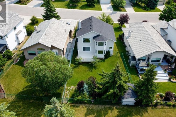 Aerial view of the backyard of a grey house with a green lawn and fence. - 120 Gleneagles Terrace, Cochrane