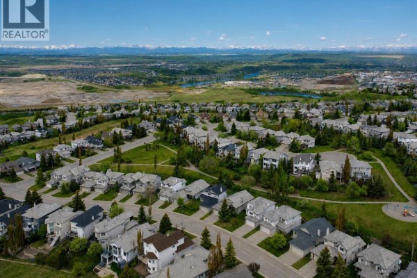 Aerial view of a suburban neighborhood with houses and distant mountains. - 120 Gleneagles Terrace, Cochrane