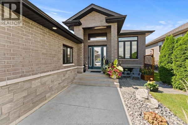 Front entrance of the house with stone steps, large windows, and decorative plants. - 120 Golfview Drive, Kingsville