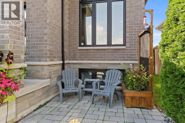 Small patio area with two grey chairs and a table, next to a planter and brick wall. - 120 Golfview Drive, Kingsville