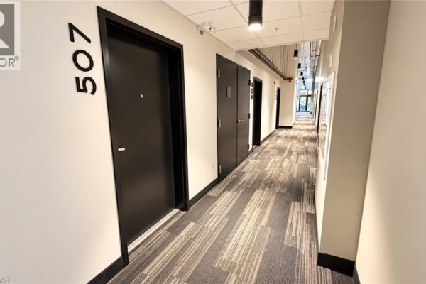 Hallway with textured carpet, black doors, and unit number 507 on the left. - 120 Huron Street Unit# 507, Guelph