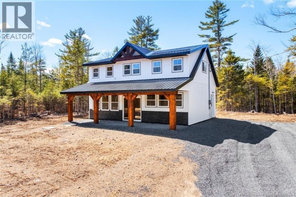 Side view of the house showcasing the porch and surrounding forest. - 120 John Chessie Dr, Yoho