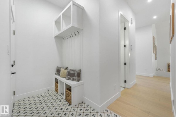 Mudroom with a white bench, cubbies, hooks, baskets, and patterned floor tiles. - 120 Ravenshire Wynd, Sherwood Park