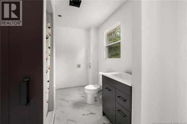 Small bathroom with white walls, a dark vanity, toilet, and marble-look floor. - 120 Saint-marcel, Acadieville