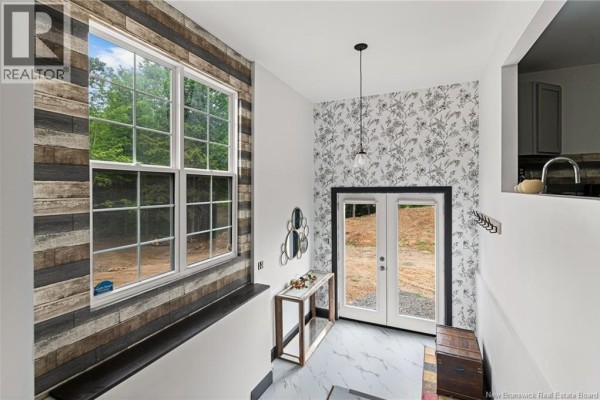 Foyer with double doors, large window, floral wallpaper, and wood-look wall paneling. - 120 Saint-marcel, Acadieville