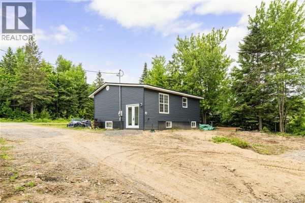 Exterior of a dark blue house with white windows, surrounded by trees. - 120 Saint-marcel, Acadieville
